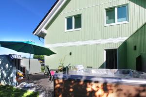 una casa verde con mesa y sombrilla en Ferienhaus Vejle, en Steinbergkirche