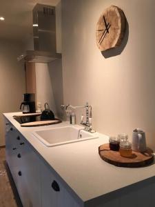 布永的住宿－La Relique ( woning voor 4 tot 6 personen )，厨房配有水槽和墙上的时钟