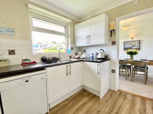 a kitchen with white cabinets and a sink and a window at Myebon in Padstow