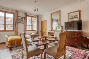 uma sala de estar com uma mesa e cadeiras e uma televisão em Bohemian & Authentic Parisian Flat - Paris 07 em Paris