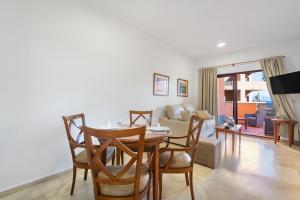 a dining room and living room with a table and chairs at Don Juan Beach Resort in Estepona