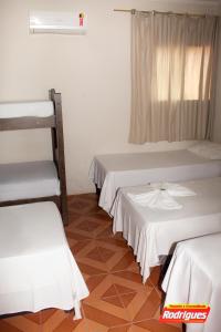a room with three beds and a window at POUSADA RODRIGUES in Barbalha