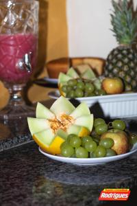 a plate of fruit on a table with apples and grapes at POUSADA RODRIGUES in Barbalha +16 photos