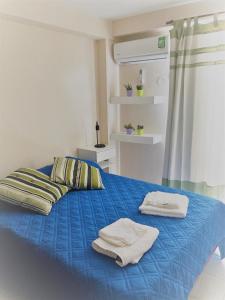Un dormitorio con una cama azul con toallas. en Balcarce 146 en San Miguel de Tucumán