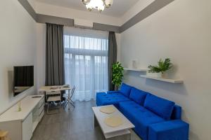 a living room with a blue couch and a table at Studia przy lotnisku od WroclawApartament-pl in Wrocław
