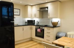 a kitchen with white cabinets and a wooden table at Bridge Cottage in Luib