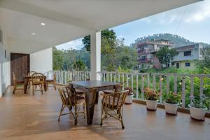een patio met een tafel en stoelen op een balkon bij Hotel Vista Bhowali, Nainital - Vegetarian in Bhowāli