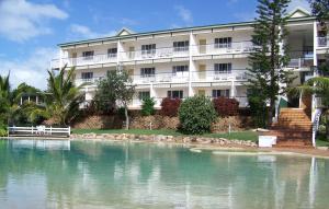 ein großes weißes Gebäude neben einem Wasserkörper in der Unterkunft K'gari Beach Resort in Fraser Island