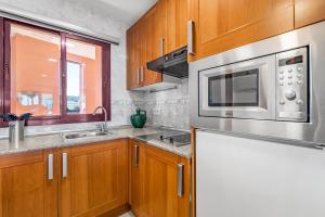 a kitchen with wooden cabinets and a microwave at Don Juan Beach Resort in Estepona +22 photos