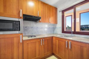 a kitchen with wooden cabinets and a microwave and a window at Don Juan Beach Resort in Estepona