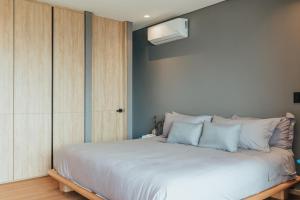 ein Schlafzimmer mit einem großen weißen Bett mit blauen Kissen in der Unterkunft Wake - branded residences in Medellín