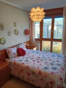 a bedroom with a bed with a floral bedspread and a window at LA ERIA I, muy soleado, Wifi, garaje, 15 min a pie al centro in Oviedo