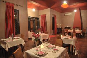 a dining room with white tables and chairs and red curtains at Boutique Hôtel palais Masandoia in Erfoud