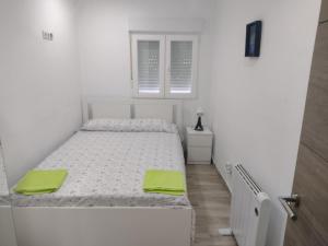 a white bedroom with a bed with green towels on it at De la Cuenca Mieres II con parking Privado in Mieres