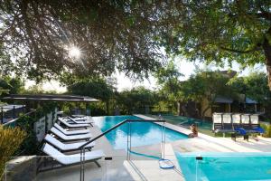 una piscina con tumbonas junto a un árbol en A Hotel Decosuites en Merlo