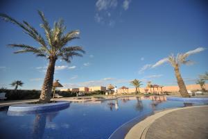 a swimming pool with palm trees in a resort at Boutique Hôtel palais Masandoia in Erfoud