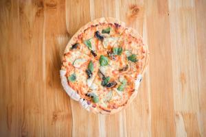 a pizza sitting on top of a wooden table at La Perla Negra - Black Pearl Eco Hostel in San Rafael