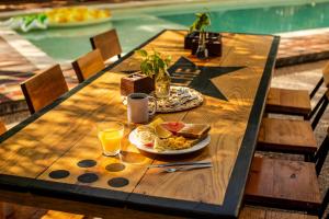 una mesa de madera con un plato de comida y bebida en Che Holbox Hostel & Bar Adults Only, en Isla Holbox