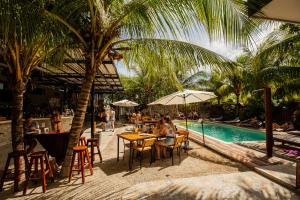 un grupo de personas sentadas en mesas junto a una piscina en Che Holbox Hostel & Bar Adults Only, en Isla Holbox