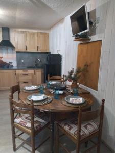 a kitchen with a wooden table with chairs and a television at Le Perce Neige in Vaujany