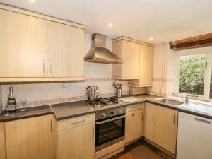 eine Küche mit Holzschränken und einem Herd mit Backofen in der Unterkunft Palmers Green Cottage in Taunton