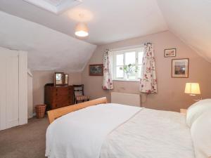 ein Schlafzimmer mit einem weißen Bett und einem Fenster in der Unterkunft Palmers Green Cottage in Taunton