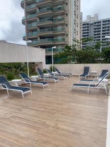 una fila di sedie seduta su un patio di fronte a un edificio di Apartamento Alto Padrão / prédio com piscina e quadra. a Guarujá