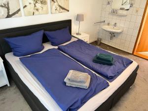 a bedroom with a bed with blue sheets and a sink at Ferienwohnung Südwind in Schashagen