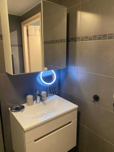 W łazience znajduje się biała umywalka i lustro. w obiekcie Even naar zee Nieuwpoort Appartement Waterkant w mieście Nieuwpoort
