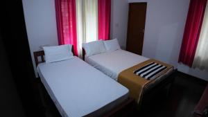 2 camas en una habitación pequeña con cortinas rojas en Thas apartment en Alwaye