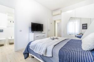 a white bedroom with a bed and a tv at Casaballi Milano MM3 Trilocale in Milan