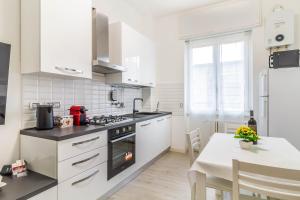 eine Küche mit weißen Geräten und einem Tisch mit einem Esszimmer in der Unterkunft Casaballi Milano MM3 Trilocale in Mailand
