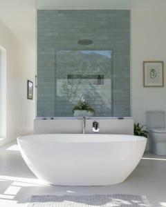 a bathroom with a white tub and a green tile wall at Magnifik Montagu in Montagu