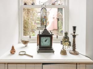 a clock sitting on a counter in front of a window at Wonderland Cottage in Cupar