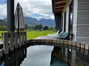 a house with an umbrella and chairs and a pool of water at Aysén Lodge - Cabaña con Tinaja in Puerto Dunn