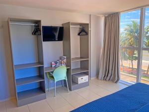 1 dormitorio con escritorio, silla y TV en Flat Beira Mar do Cabo Branco Quarto com linda vista para o mar, en João Pessoa