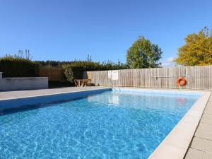 una piscina en un patio trasero con una valla de madera en Alder Lodge en Newton Abbot