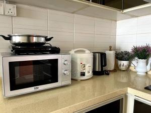 a kitchen counter with a microwave and a stove at Homestay TTDI ADINA 710 Shah Alam,Sek 13,MSU,3Bedroooms in Shah Alam