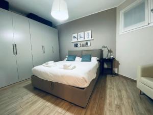 una camera da letto con un grande letto con lenzuola bianche e cuscini blu di NEW - Nuovo appartamento in centro a San Donato Milanese