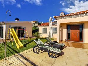 a backyard with two chairs and a slide at Casa Del Sol by LovelyStay in Relógio do Poiso