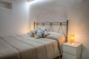 Dormitorio con cama con almohada y lámpara en Home Pedra, en Ceglie Messapica