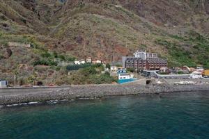 eine Stadt an der Seite eines Berges neben dem Wasser in der Unterkunft MAKTUB SUNSET COTTAGE A in Paul do Mar