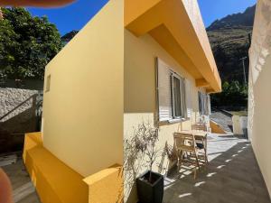 ein gelbes Haus mit einem Tisch und Stühlen auf einer Terrasse in der Unterkunft MAKTUB SUNSET COTTAGE A in Paul do Mar + 7 Fotos