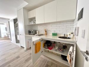 una cocina con armarios blancos y fregadero en Cozy & sunny studio in Saavedra en Buenos Aires