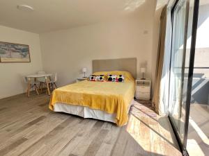 um quarto com uma cama com uma colcha amarela em Cozy & sunny studio in Saavedra em Buenos Aires