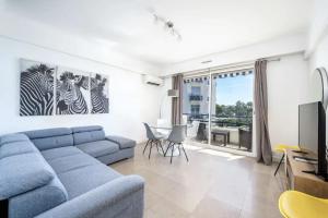 a living room with a blue couch and some zebras on the wall at Croisette - 2 Chambres - Vue Epoustouflante in Cannes