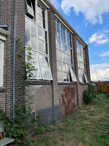 een bakstenen gebouw met ramen aan de zijkant bij Mooi appartement in Werkplaats in Kampen