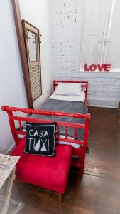 Casa Tuxi في ريو دي جانيرو: سرير احمر وكرسي احمر في الغرفه