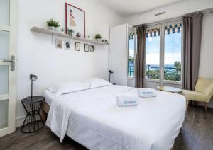 a bedroom with a large white bed and a window at Croisette - 2 Chambres - Vue Epoustouflante in Cannes