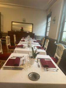 un comedor con mesas blancas y servilletas rojas en Le Grand Monarque Donzy, en Donzy